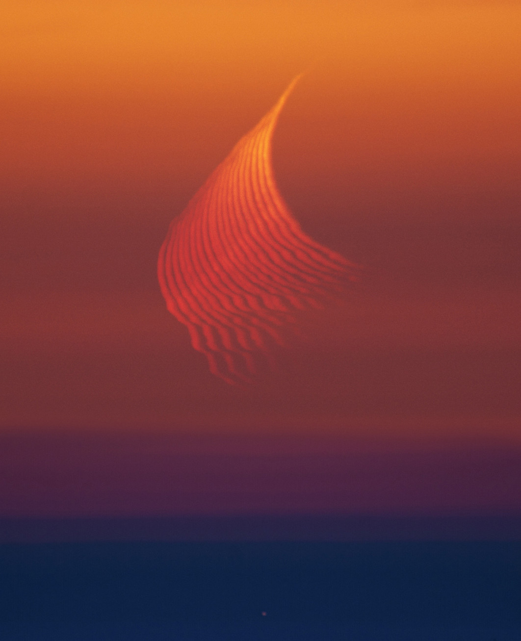 Fot. Marcella Giulia Pace, &quot;The Trace of Refraction&quot;, 1. miejsce w kat. Our Moon / ZWO Astronomy Photographer of the Year 2025

Zdjęcie ukazuje zjawisko refrakcji atmosferycznej: światło Księżyca, przechodząc przez gęste warstwy atmosfery blisko horyzontu, załamuje się w sposób podobny do promieni światła w pryzmacie. Czerwony odcień Księżyca powodowany jest przez tzw. rozpraszanie Rayleigha (mniejsze cząsteczki w atmosferze silniej rozpraszają krótsze długości fal, przez co przeważają dłuższe fale - czyli czerwień).