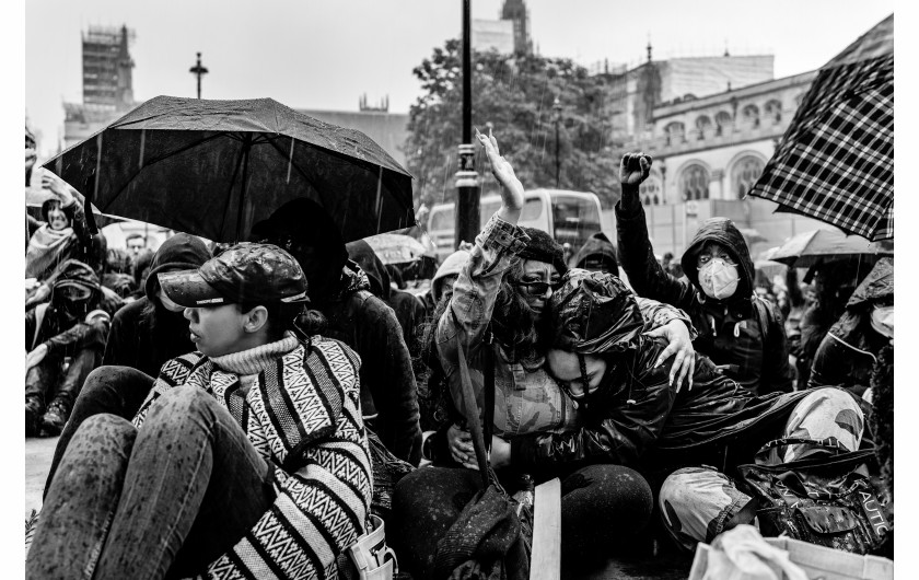 fot. Chris Mozyro, Black Lives MatterBlack Lives Matter to międzynarodowy ruch na rzecz praw człowieka, wywodzący się ze społeczności afroamerykańskiej, który prowadzi kampanie przeciwko przemocy i systemowemu rasizmowi wobec Czarnych. BLM regularnie organizuje protesty przeciwko brutalności policji i zabójstwom Czarnych przez policję, a także szerszym kwestiom, takim jak profilowanie rasowe i nierówność rasowa w systemie sądownictwa karnego Stanów Zjednoczonych. Ruch powrócił na pierwsze strony gazet i zyskał dalsze międzynarodowe zainteresowanie podczas globalnych protestów po śmierci George'a Floyda w 2020 roku w Minneapolis w Minnesocie. Floyd zmarł po aresztowaniu za rzekome wykorzystywanie fałszywych pieniędzy do kupowania papierosów. Biały policjant klęczał na jego szyi przez osiem minut i 46 sekund, co doprowadziło do jego śmierci. Wydarzenia związane z aresztowaniem, śmiercią i działaniami funkcjonariuszy doprowadziły do międzynarodowych protestów Black Lives Matter, wezwań do reformy policji i ustawodawstwa dotyczącego nierówności rasowych. Protesty wybuchły i trwają od tego czasu w wielu miastach USA, Australii, Francji, Holandii i Wielkiej Brytanii. Zdjęcia te wykonano 6 czerwca 2020 roku podczas londyńskiego protestu. Znalazłem się w centrum protestów, doświadczając całej gamy ludzkich emocji i obserwując niecodzienne zachowanie. Fakt, że protest miał miejsce podczas pandemii Covid-19, sprawia, że wydarzenie to jest jeszcze bardziej znaczące. Około godziny 23:00, po wielu godzinach stania w wściekłym tłumie, zabrano mnie na policyjne śledztwo. Oficer przesłuchał mnie i sprawdził dowód. W końcu udało mi się wyjechać, ale odradzono mi powrót do centrum miasta w ciągu 24 godzin, ponieważ groziłoby to aresztowaniem.Chris Mozyro - Chociaż obecnie mieszka w Londynie, urodził się i wychował na Litwie. Po ukończeniu polskiej szkoły podstawowej, ukończył z dyplomem Zawodowe Centrum Technologii i Biznesu w Wilnie. Praktykowanie kickboxingu we wczesnych latach pomogło mu rozwinąć dyscyplinę i odporność. Obie te cechy przydają mu się obecnie w karierze fotografa.Szybko odkrył, że fotografia jest fantastycznym sposobem na uchwycenie szerokiej gamy ludzkich emocji, i że ten temat wydaje mu się niezwykle pociągający. Wiedząc, że jego były nauczyciel jest zapalonym fotografem z dużym doświadczeniem, poprosił go o mentoring. W styczniu 2019 roku Chris wziął udział w swoich pierwszych warsztatach fotograficznych zorganizowanych przez Mariusza Śmiejeka, założyciela All Media Academy w Londynie. Wkrótce potem, uczestniczył w trzech kolejnych przedsięwzięciach tego typu, w tym w warsztatach wyjazdowych na Sycylii. Niedługo potem miał szczęście zostać zaproszony do Warszawy przez Szeroki Kadr na przegląd portfolio fotograficznego.Jego twórczość została dostrzeżona przez Szeroki Kadr i opublikowana w EYEphoto Magazine. W tym roku znalazł się także w półfinale konkursu URBAN 2020 Photo Awards.