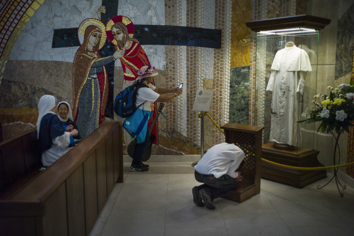 fot. Wojciech Grzędziński, dla Aleteia.pl. 3. miejsce w kategorii kultura i Rozrywka.
Kraków. Światowe Dni Młodzieży to spotkania młodych katolików z papieżem zapoczątkowane w 1986 roku przez Jana Pawła II w Rzymie. Wierni z całego świata spotykają się co dwa lata w różnych miejscach, by wspólnie się modlić, poznawać i bawić. W 2016 roku w Krakowie na spotkanie z papieżem Franciszkiem przybyły prawie 2 mln pielgrzymów. Na zdjęciu: sanktuarium w Krakowie-Łagiewnikach; pielgrzym modli się przed zakrwawioną sutanną Jana Pawła II, inni fotografują i rozmawiają. Zdjęcie pochodzi z fotoreportażu. 24 lipca 2016.