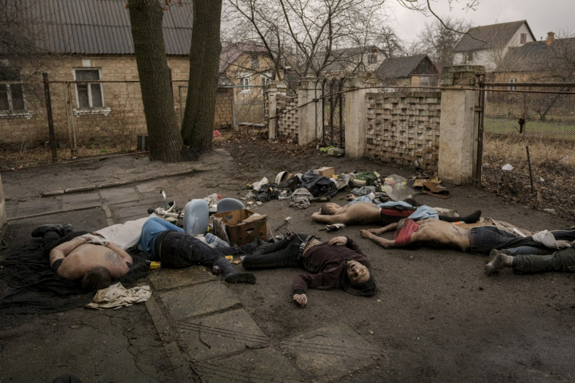 fot. Vadim Ghirda, Nieruchome ciała mężczyzn, niektóre z rękami związanymi za plecami, leżą na ziemi w Buczy, Ukraina, 3 kwietnia 2022. Mord w Buczy był tym, co rosyjscy żołnierze w przechwyconych rozmowach telefonicznych nazywali "zachistką" - czystką. Rosjanie polowali na ludzi z list przygotowanych przez ich służby wywiadowcze i chodzili od drzwi do drzwi, aby zidentyfikować potencjalne zagrożenia. Ci, którzy nie przeszli tej filtracji, w tym ochotnicy i cywile podejrzani o pomoc ukraińskim oddziałom, byli torturowani i rozstrzeliwani.