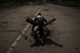 fot.  Felipe Dan, Ciało niezidentyfikowanego mężczyzny z wojskowymi emblematami leży na barierze drogowej w pobliżu wsi odzyskanej przez siły ukraińskie na obrzeżach Charkowa, Ukraina, 1 maja 2022.