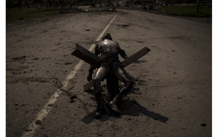 fot.  Felipe Dan, Ciało niezidentyfikowanego mężczyzny z wojskowymi emblematami leży na barierze drogowej w pobliżu wsi odzyskanej przez siły ukraińskie na obrzeżach Charkowa, Ukraina, 1 maja 2022.