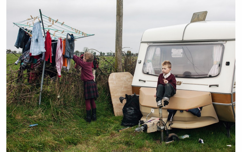 fot. Birte Kaufmann, „Travellersi”

Projekt „Travellersi” dokumentuje życie członków najliczniejszej mniejszości w Irlandii. Mowa o współczesnych nomadach wywodzących się z tradycji migracji zarobkowej. Dzisiaj cel tułaczki się zmienił, tzw. travellersi próbują na nowo odnaleźć swoją tożsamość w społeczeństwie Europy Zachodniej. Styl życia irlandzkich koczowników jest dosyć nietypowy, dlatego spotyka się z brakiem akceptacji ze strony reszty obywateli. Ci ludzie żyją jakby w równoległej rzeczywistości, która rządzi się swoimi prawami, i w której obowiązuje tradycyjny podział ról. Osoby z zewnątrz rzadko mają wstęp do tego hermetycznego świata.

Po dziś dzień niektóre rodziny rozbijają nielegalne obozowiska przy drodze. Żyją bez prądu, bieżącej wody, ani sanitariatów, choć władze zapewniają im specjalne pola kempingowe, gdzie mogą parkować swoje wozy.

Pierwszy raz do Irlandii wybrałam się VW „ogórkiem” w 2011 roku. Na zdjęciach chciałam uchwycić styl życia travellersów i wartości, którymi się kierują. Nie zamierzałam idealizować ich zwyczajów. Chciałam pokazać świat współczesnych nomadów, którzy polują na króliki, nie mogą się obejść bez koni, od dziecka zmagają się z trudami życia i walczą z nudą.

Podczas mojego pierwszego spotkania z irlandzkimi tułaczami poznałam pewną liczną rodzinę. W miarę upływu czasu zdobywałam ich zaufanie. W końcu zgodzili się, żebym z nimi zamieszkała. Ja i mój aparat staliśmy się częścią ich codziennego życia