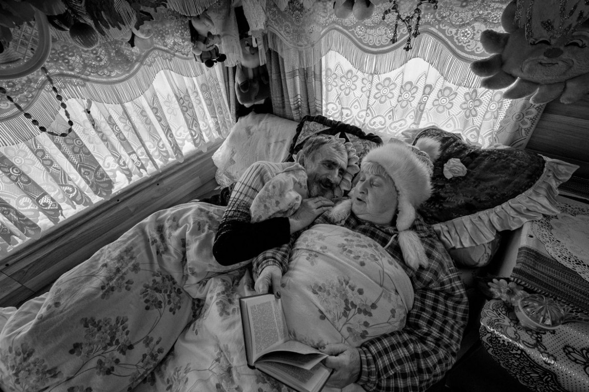 fot. Tadeusz Koniarz, Agencja Fotograficzna East News. Nagroda Adobe i Adobe Stock.
Miedziana Góra. Barbara i Tadeusz Buczyńscy to ludowi artyści nieprofesjonalni. Mają po 65 lat. Tworzą rzeźby proste, kolorowe, radosne – Baby-Jagi, czarownice, diabły i inne postaci rodem z baśni to ich Zaczarowana Galeria. Od kilku lat ich domem jest przyczepa kempingowa, symbol wędrówki, ale także efekt trudności materialnych, z jakimi się borykają. Gdy na zewnątrz jest zimno, najlepiej schować się w łóżku. Wtedy Barbara czyta na głos książki swojemu ukochanemu. 1 grudnia 2016.