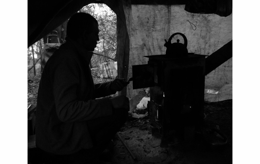 Fot. Maciej Grzybowski, 1. miejsce w kat. Documentary Project / Grand Press Photo 2024Ela, Darek i Mirek są w bezdomności od wielu lat. Mieszkają w lesie nad rzeką, na obrzeżach miasta. Opiekują się dwoma psami Florą i Jogim. Ela przez kilkanaście lat pracowała w zakładach farmaceutycznych. Jest wdową, jej syn mieszka za granicą. Obecnie bezrobotna. Darek, partner Eli, podejmuje się prac dorywczych na budowach i w firmach sprzątających miasto. Sam zbudował wszystkie domki. Mirek pochodzi z Pomorza, jest wolnym duchem. Często wychodzi w nocy zbierać złom, który potem sprzedaje.
W Polsce około 30 tysięcy osób znajduje się w kryzysie bezdomności, z czego ponad 80 proc. stanowią mężczyźni.
