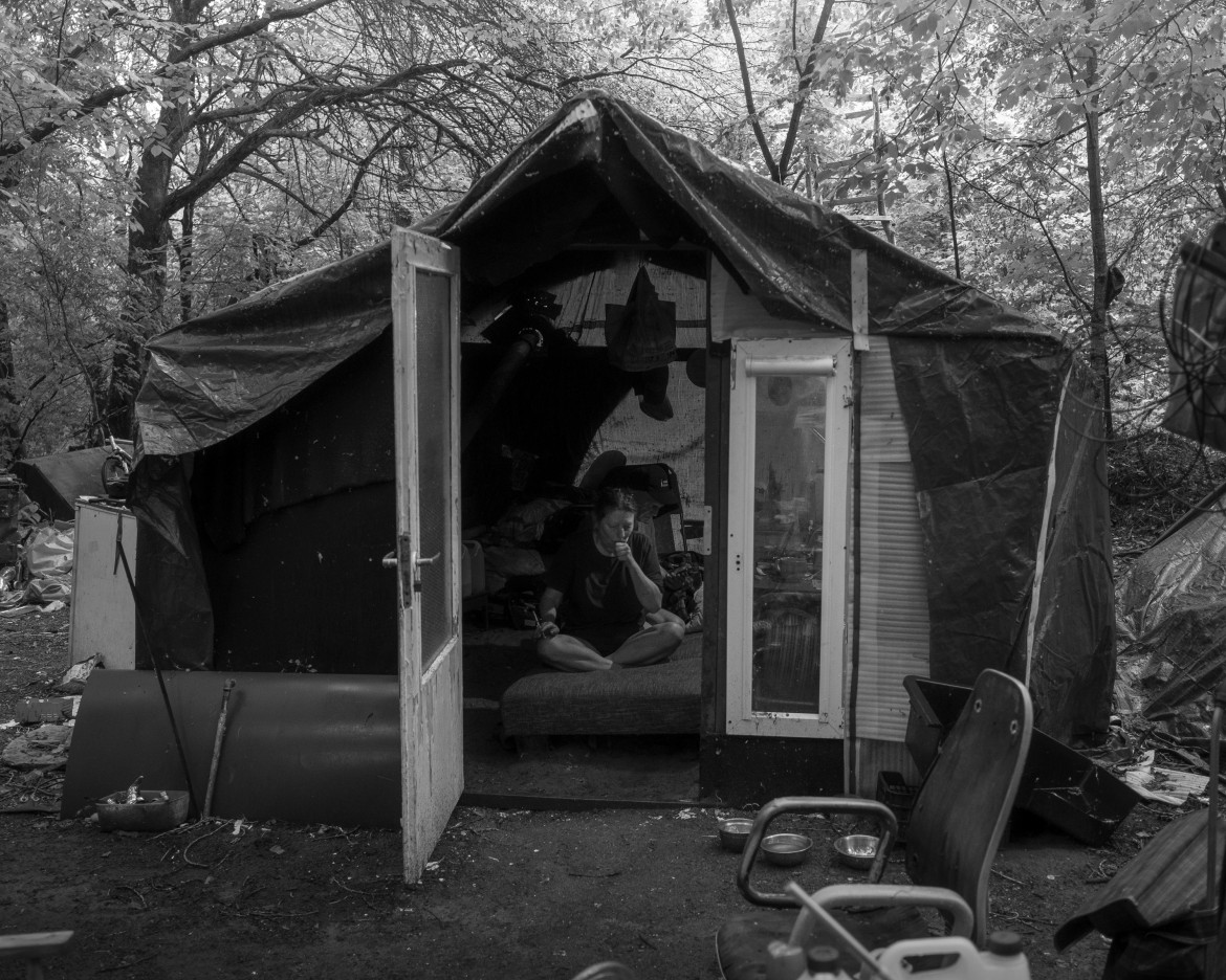 Fot. Maciej Grzybowski, 1. miejsce w kat. Documentary Project / Grand Press Photo 2024<br></br><br></br>Ela, Darek i Mirek są w bezdomności od wielu lat. Mieszkają w lesie nad rzeką, na obrzeżach miasta. Opiekują się dwoma psami Florą i Jogim. Ela przez kilkanaście lat pracowała w zakładach farmaceutycznych. Jest wdową, jej syn mieszka za granicą. Obecnie bezrobotna. Darek, partner Eli, podejmuje się prac dorywczych na budowach i w firmach sprzątających miasto. Sam zbudował wszystkie domki. Mirek pochodzi z Pomorza, jest wolnym duchem. Często wychodzi w nocy zbierać złom, który potem sprzedaje.
W Polsce około 30 tysięcy osób znajduje się w kryzysie bezdomności, z czego ponad 80 proc. stanowią mężczyźni.