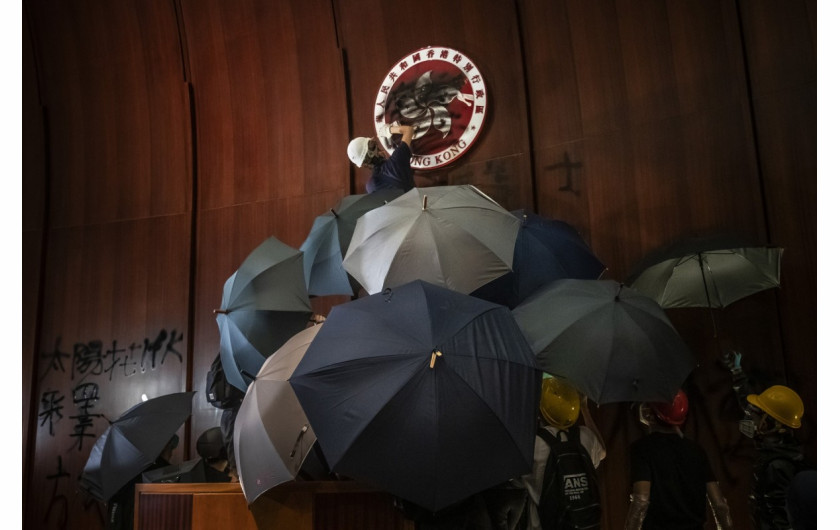 fot. Tyrone Siu. Mężczyzna sprejuje herb Hong Kongu po tym jak protestujący wdarli się do siedziby Rady Legislacyjnej Hong Kongu w dniu 22 rocznicy przekazania władzy przez Wielką Brytanię Chinom / Pulitzer Prize for Breaking News Photography 2020