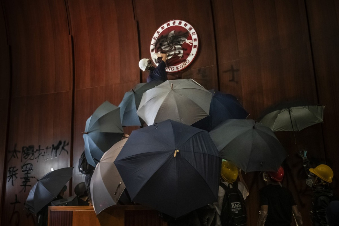 fot. Tyrone Siu. Mężczyzna sprejuje herb Hong Kongu po tym jak protestujący wdarli się do siedziby Rady Legislacyjnej Hong Kongu w dniu 22 rocznicy przekazania władzy przez Wielką Brytanię Chinom / Pulitzer Prize for Breaking News Photography 2020