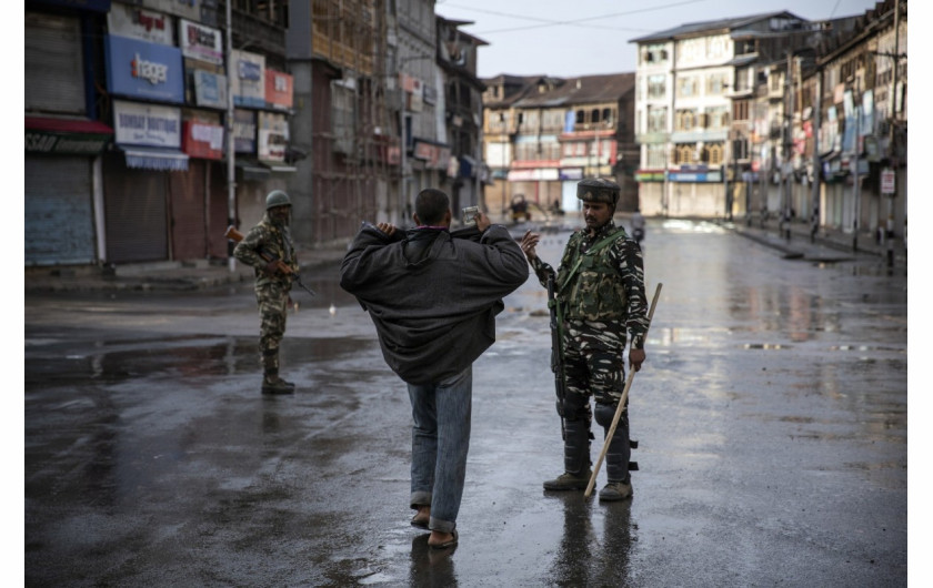 fot. Dar Yasin. Członek indyjskiego oddziału paramilitarnego nakazuje obywatelowi Kaszmiru rozpięcie kurtki przed rewizją podczas godziny policyjnej w Srinagar. Na ulicach miasta pojawiły się punkty kontrolne i żołnierze. 8 sierpnia 2019 / The Pulitzer Prize 2020 for Feature Photography