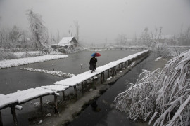 fot. Dar Yasin. Mężczyzna spaceruje po pieszym moście na jeziorze Dal w Srinagar. 13 grudnia 2019 / The Pulitzer Prize 2020 for Feature Photography