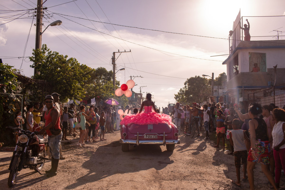 fot. Diana Markosia, Magnum Photos, "The Cubanitas", 1. miejsce w kategorii Contemporary Issues.
15 urodziny w kulturze latynoskiej oznaczają wejście kobiety w dorosłość. Rodziny urządzają z tej okazji kosztowne przyjęcia, a solenizantki ubierane i traktowane są jak księżniczki. Na Kubie tradycja ta wyewoluowała w przedstawienie w skład którego wchodzą sesje zdjęciowe i wideo. Na zdjęciu 15-letnia Pura podróżująca przez swoją dzielnicę w kabriolecie z lat 50., otoczona przez mieszkańców, którzy zebrali się, by świętować jej urodziny.