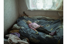 Fot. Florian Bachmeier, "Beyond the Trenches", nagroda w kat. regionalnej Europe / World Press Photo 2025<br></br><br></br>Anhelina (6), która doznała traumy i cierpi na ataki paniki po ucieczce ze swojej wioski, leży w łóżku w nowym domu. Borszcziwka, Ukraina, 7 marca 2024 r. <br></br><br></br>
Trwający konflikt w Ukrainie zmusił rodzinę Anheliny do szukania schronienia. Anhelina mieszka teraz ze swoją babcią Larisą w Borszcziwce, 95 kilometrów od Kupiańska, podczas gdy jej matka mieszka i pracuje w Charkowie - około godziny drogi stamtąd. Fotograf chciał rzucić światło na dzieci, które dorastały w otoczeniu przemocy. Ich niewinność została złamana, ale ich duch przetrwał, gdy przystosowywały się do nowego życia.