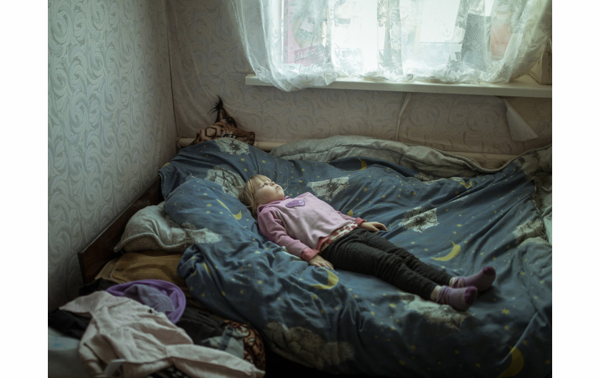 Fot. Florian Bachmeier, Beyond the Trenches, nagroda w kat. regionalnej Europe / World Press Photo 2025Anhelina (6), która doznała traumy i cierpi na ataki paniki po ucieczce ze swojej wioski, leży w łóżku w nowym domu. Borszcziwka, Ukraina, 7 marca 2024 r. 
Trwający konflikt w Ukrainie zmusił rodzinę Anheliny do szukania schronienia. Anhelina mieszka teraz ze swoją babcią Larisą w Borszcziwce, 95 kilometrów od Kupiańska, podczas gdy jej matka mieszka i pracuje w Charkowie - około godziny drogi stamtąd. Fotograf chciał rzucić światło na dzieci, które dorastały w otoczeniu przemocy. Ich niewinność została złamana, ale ich duch przetrwał, gdy przystosowywały się do nowego życia.