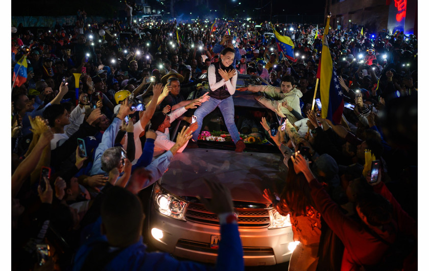 Fot. Gabriela Oráa, Reuters,  The Last Hope, nagroda w kat. regionalnej South America / World Press Photo 2025Liderka wenezuelskiej opozycji María Corina Machado pozdrawia zwolenników z dachu pojazdu podczas wiecu wyborczego opozycyjnego kandydata na prezydenta Edmundo Gonzáleza Urrutii. Mérida, Wenezuela, 25 czerwca 2024 r.

W 2023 r. María Corina Machado wygrała prawybory opozycyjne, aby rzucić wyzwanie Nicolásowi Maduro w wyborach prezydenckich, ale władze Wenezueli zabroniły jej kandydowania. W rezultacie poparła byłego ambasadora Edmundo Gonzáleza Urrutię jako kandydata opozycji i poprowadziła jego kampanię polityczną w całym kraju. Po wyborach władze ogłosiły Maduro zwycięzcą, ale opozycja zakwestionowała wyniki, powołując się na wyniki głosowania, które wskazywały na zwycięstwo Gonzáleza. Zarzuty dotyczące nieprawidłowości wyborczych doprowadziły  do zakwestionowania legalności wyniku w wielu krajach. Chociaż Maduro zachował władzę, a González został zmuszony do emigracji, Machado pozostaje w ukryciu jako lider opozycji i kluczowa postać opowiadająca się za zmianami politycznymi.