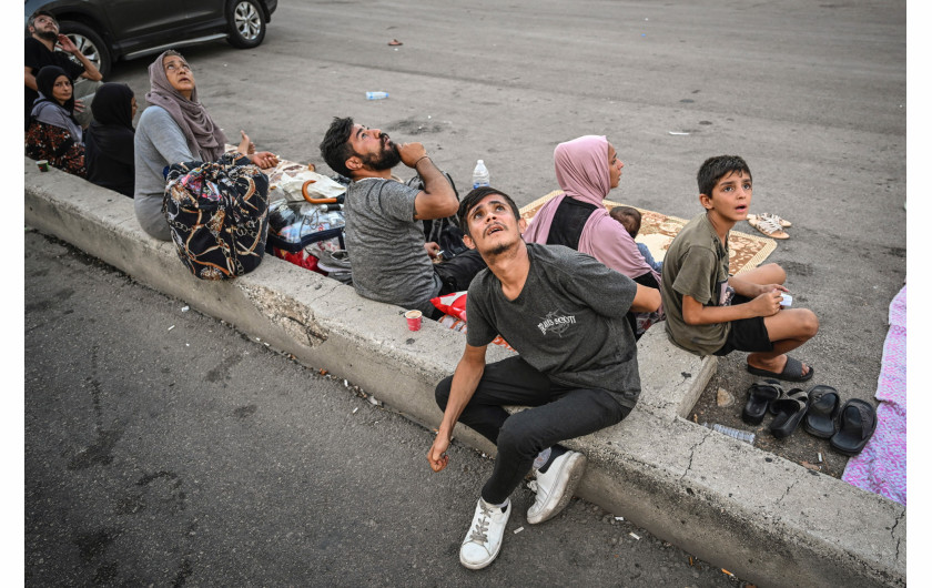 Fot. Murat Şengül, Anadolu Agency, Drone Attacks in Beirut, nagroda w kat. regionalnej West , Central & South Asia / World Press Photo 2025Ludzie spoglądają w górę z niepokojem podczas ataku izraelskiego drona. Odrzutowce i drony często latają na niskich wysokościach, powodując strach i niepokój. Liban, 29 września 2024 r.
Ataki transgraniczne między Izraelem a libańskim Hezbollahem - trwające od wybuchu wojny w Strefie Gazy - gwałtownie nasiliły się we wrześniu 2024 roku. Izrael ogłosił nowy cel wyeliminowania grupy bojowników, najpierw rozpoczynając naloty na południowy Liban, a później ofensywę lądową. Bejrut, początkowe schronienie dla uciekających przed nalotami w południowym Libanie, sam znalazł się pod ostrzałem, gdy ataki rozprzestrzeniły się na północ. Od 27 września Izrael atakował budynki, w tym bloki mieszkalne w Dahiyeh, twierdząc, że Hezbollah ma siedzibę na gęsto zaludnionych przedmieściach.