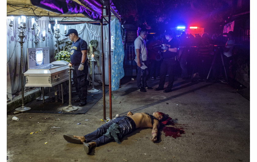 fot. Ezra Acayan, The Death of Michael Nadayo, 2. miejsce w kategorii Spot News.

Ciało Michaela Nadayo leży na ulicy obok trumny, wokół której zebrali się  żałobnicy. Quezon City, Filipiny, 31 sierpnia 2018. Po objęciu władzy w 2016 roku prezydent Rodrigo Duterte uruchomił antynarkotykową ofensywę i rzekomo rozkazał zaostrzenie środków stosowanych wobec podejrzanych. Według Amnesty International doprowadziło to do łamania praw człowieka i samosądów, zarówno ze strony policji, jak i cywilów. Według rządowych agencji śmierć poniosło ponad 5 tys. osób, natomiast nieoficjalne źródła mówią nawet o 12 tys. W czerwcu 38 państw członkowskich ONZ wezwało prezydenta Duterte do zaprzestania czystek i skupienia się na przyczynach wojny narkotykowej.