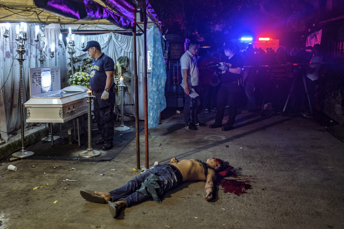 fot. Ezra Acayan, "The Death of Michael Nadayo", 2. miejsce w kategorii Spot News.

Ciało Michaela Nadayo leży na ulicy obok trumny, wokół której zebrali się  żałobnicy. Quezon City, Filipiny, 31 sierpnia 2018. Po objęciu władzy w 2016 roku prezydent Rodrigo Duterte uruchomił antynarkotykową ofensywę i rzekomo rozkazał zaostrzenie środków stosowanych wobec podejrzanych. Według Amnesty International doprowadziło to do łamania praw człowieka i samosądów, zarówno ze strony policji, jak i cywilów. Według rządowych agencji śmierć poniosło ponad 5 tys. osób, natomiast nieoficjalne źródła mówią nawet o 12 tys. W czerwcu 38 państw członkowskich ONZ wezwało prezydenta Duterte do zaprzestania czystek i skupienia się na przyczynach wojny narkotykowej.