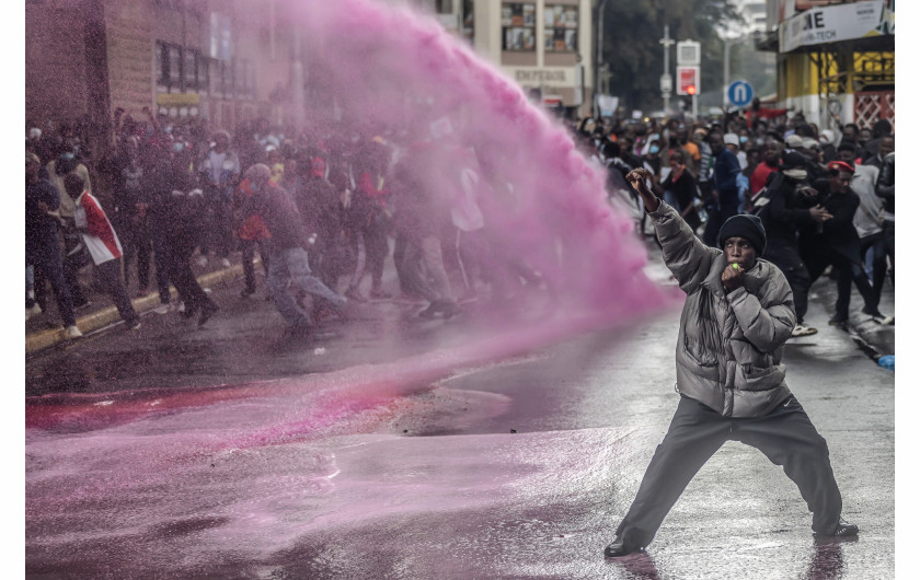 Z cyklu: Kenya's Youth Uprising
fot. Luis Tato / Agence France-Presse / World Press Photo 2025



W 2024 roku kenijski Skarb Państwa zaproponował wprowadzenie dodatkowych podatków na codzienne produkty, aby zwiększyć dochody państwa i zmniejszyć wysokie zadłużenie kraju. Propozycja ta wywołała falę protestów, zainicjowanych przez młodych Kenijczyków, którzy organizowali się za pośrednictwem mediów społecznościowych. 25 czerwca demonstranci wtargnęli do Parlamentu i starli się z policją; wielu zginęło lub zostało uprowadzonych, a setki odniosły obrażenia. Choć prezydent William Ruto wycofał kontrowersyjną ustawę, protesty trwają nadal w 2025 roku, podsycane gniewem wobec trudnej sytuacji gospodarczej, korupcji, brutalności policji i brakiem zaufania do klasy politycznej. W całym kraju młodzi ludzie stali się siłą napędową, domagając się odpowiedzialności i głębokich reform systemowych.