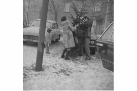 Mężczyzna i kobieta obwiązują sznurkiem choinkę. Widoczny samochód Syrena 105 i Fiat 125p. W tle kamienica przy ul. Polnej 48, Warszawa, 1976 / Narodowe Archiwum Cyfrowe