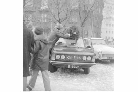 Mężczyzna mocuje choinkę na dachu samochodu osobowego Fiat 125p. Obok samochód Syrena 105, w tle kamienica przy ul. Polnej 52, Warszawa, 1976 / Narodowe Archiwum Cyfrowe