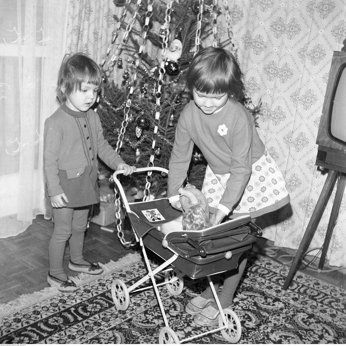 Dzieci z wózkiem dla lalek. W tle choinka, 1976 / Narodowe Archiwum Cyfrowe