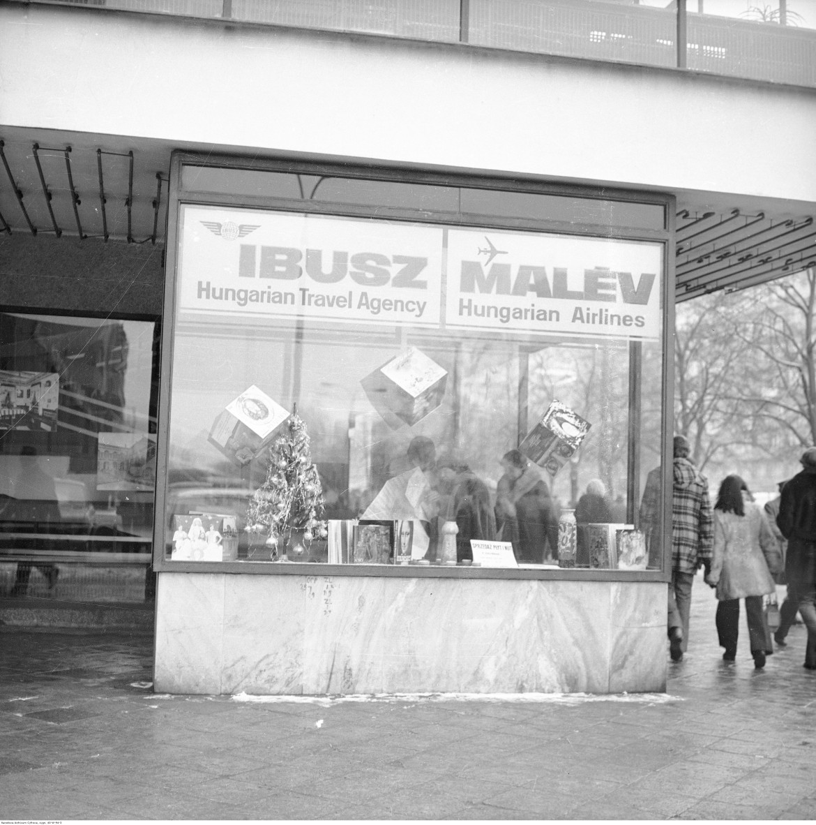 Gablota reklamowa z choinką i reklamami płyt winylowych. Widoczny szyld "IBUSZ - Hungarian Travel Agency" i "MALEW - Hungarian Airlines", Warszawa, 1976-82 / Narodowe Archiwum Cyfrowe