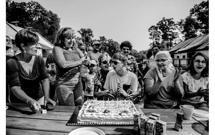 fot. Dawid Stube, I miejsce w kategorii Projekt Dokumentalny

Gniezno, Jarosławiec. Igor ma 19 lat. Chłopcy w tym wieku zaczynają czerpać garściami z życia: dojrzewają, przeżywają pierwsze bunty, pierwsze miłości, odkrywają świat. Igor nie ma tego. Cierpi na rzadką chorobę genetyczną: zespół kociego krzyku. Codziennie wraz z matką walczą o to, by odkrywany przez niego świat choć trochę przypominał ten normalny. Na początku właśnie pokazanie takiego świata było dla mnie celem projektu. Jednak im dłużej fotografowałem, tym bardziej wyłaniał mi się obraz dwojga ludzi, którzy mimo olbrzymich problemów w codziennej walce zbudowali ze sobą potężną więź: między matką a synem. Filarem tej więzi jest miłość. Ta głęboka relacja daje im siłę.
Z projektu, który był budowany przez cztery lata, wyłania się przede wszystkim obraz niezwykłej pielęgnacji miłości. Ale także obraz chłopca samotnego, zagubionego. W tle jednak zawsze jest czuwająca nad nim matka. Ona jest dla niego filarem, na którym może się oprzeć w trudnej codzienności – a on dla niej.