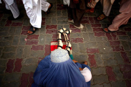 fot. Moe Zoyari | Ludzie mijają ubogą kobietę w burce i jej córkę, która straciła nogi podczas wojny z talibami w Kabulu w Afganistanie.