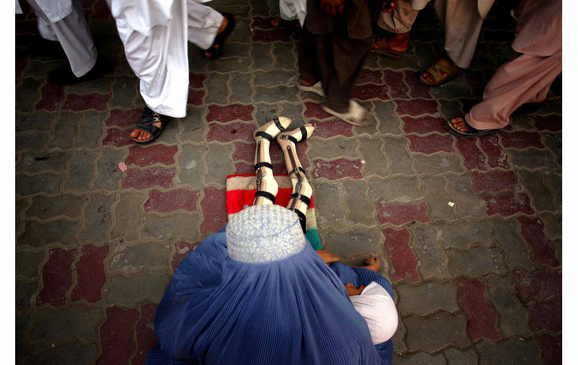 fot. Moe Zoyari | Ludzie mijają ubogą kobietę w burce i jej córkę, która straciła nogi podczas wojny z talibami w Kabulu w Afganistanie.